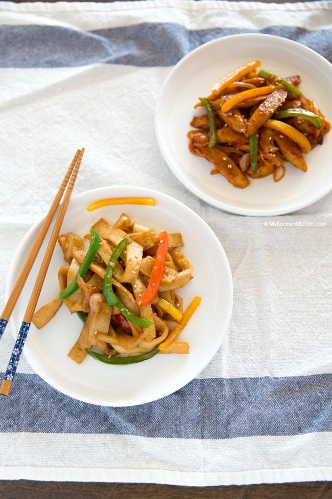 Two different styles of Korean fish cakes are served on white plates.