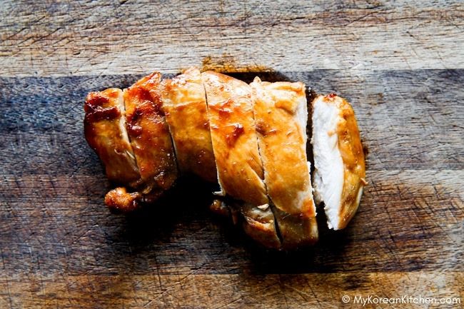 Sliced chicken thigh fillets on a wooden cutting board.