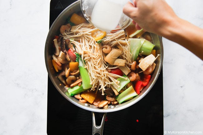 Pouring slurry over mushrooms and vegetables to thicken sauce.