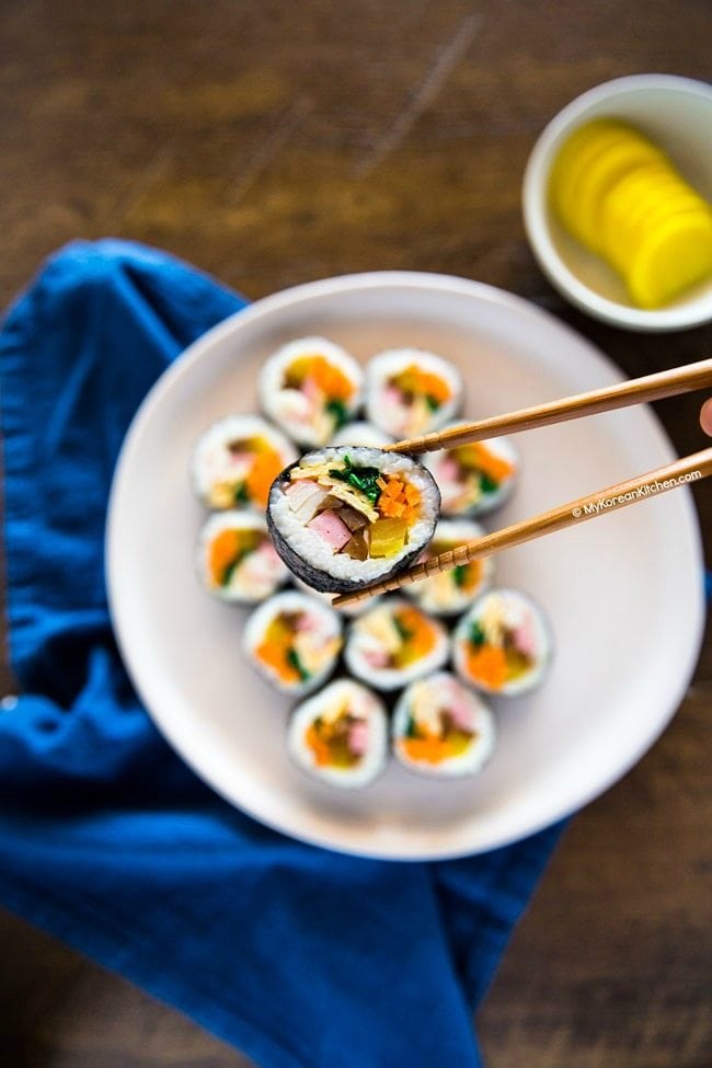 Holding kimbap with chopsticks