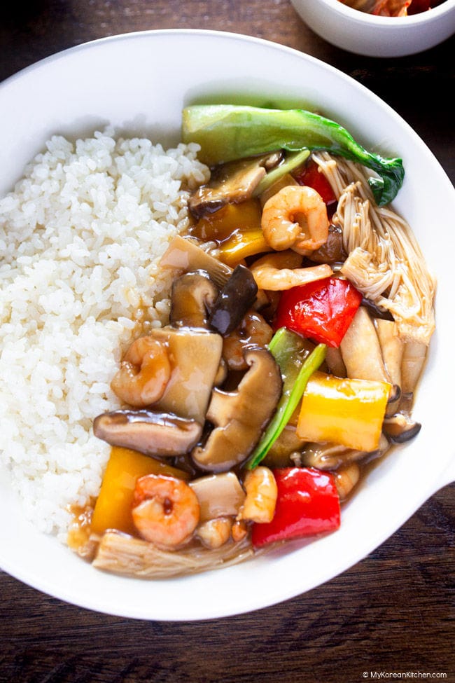 Close-up photo of cooked mushrooms and vegetables served over rice.