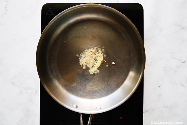 Minced garlic browning in a stainless steel pan.