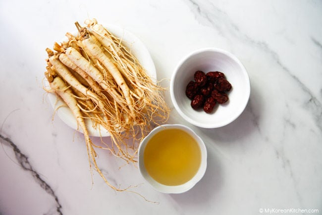 Fresh ginseng, dried jujube, and honey on the marble bench top.