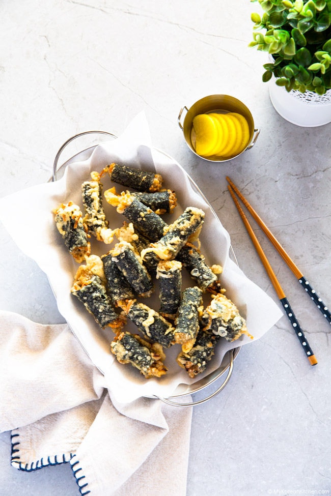 Gimmari is served on an oval-shaped tray. It is also served with yellow pickled radish and chopsticks.