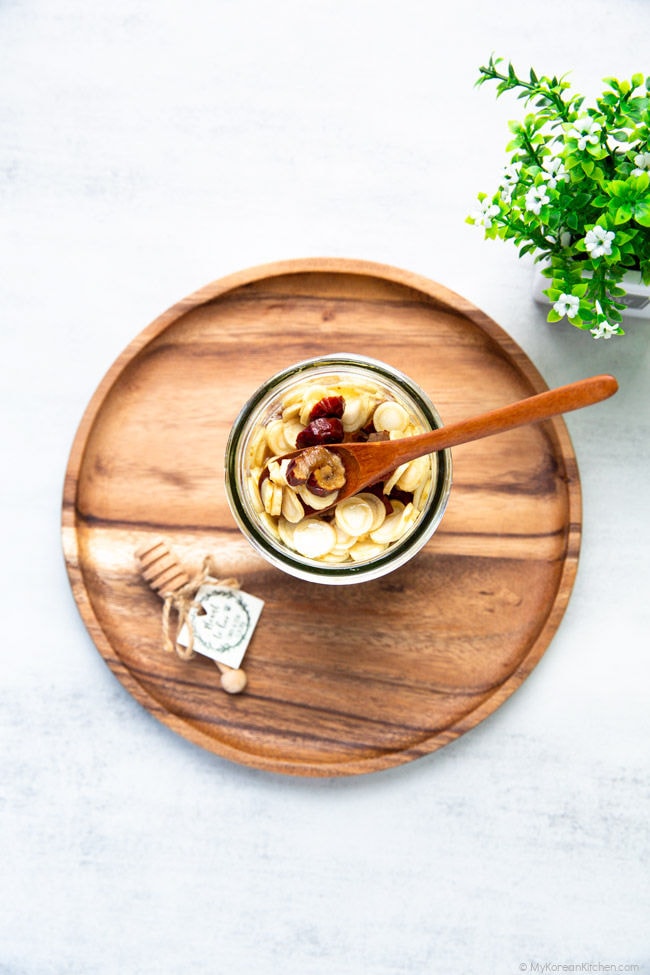 Sliced ginseng, marinated in honey, in a glass jar.