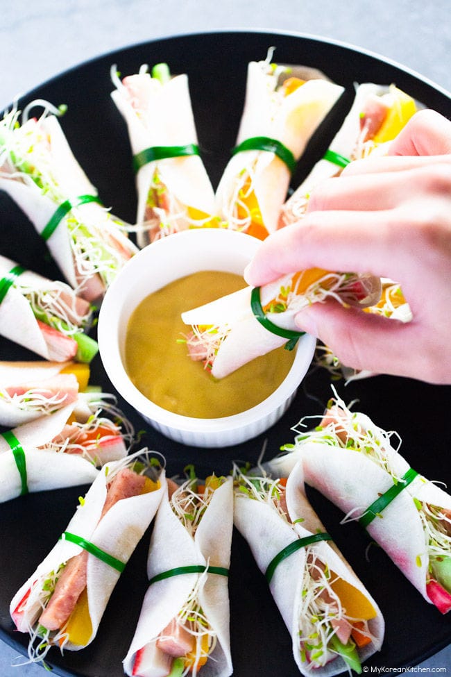 Dipping a radish wrap into a sauce bowl.