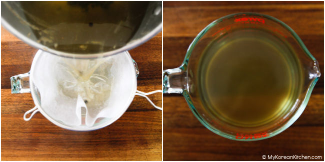 Straining beef broth into a large glass measuring cup.