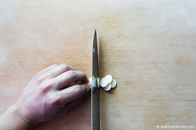 Thinly slicing ginseng.