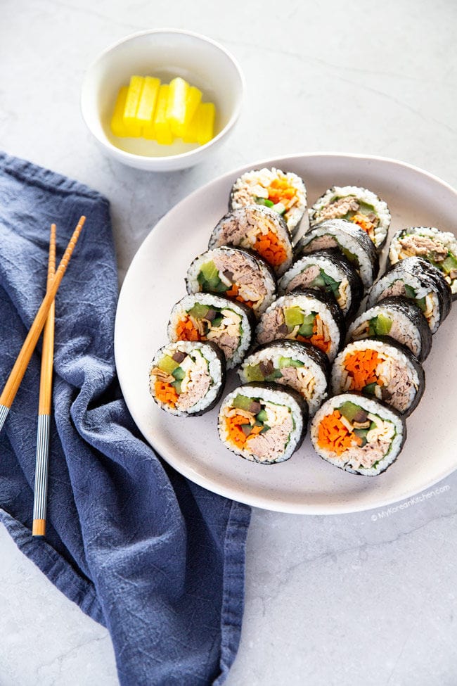 Tuna kimbap lined up on a white plate.