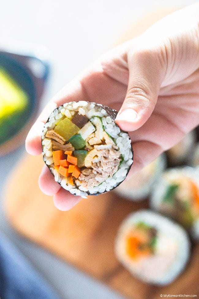 Holding a sliced tuna kimbap.