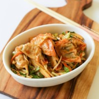 Sweet and spicy Korean dumpling salad (bibim mandu) served in a white oval bowl.