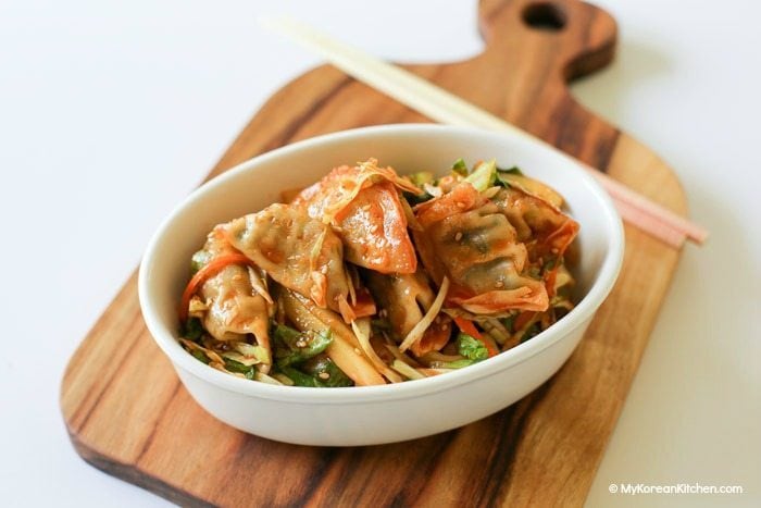 Sweet and spicy Korean dumpling salad (bibim mandu) served in a white oval bowl.
