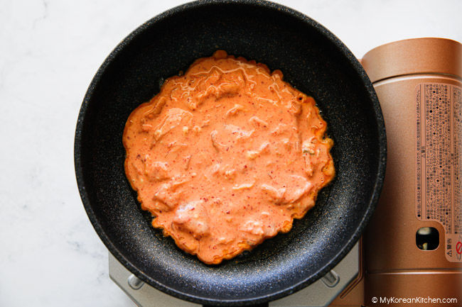 Kimchi pancake just placed in a pan over a portable gas burner.