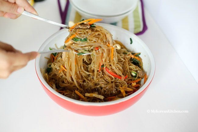 Mixing noodles, meat and vegetables together in a large bowl