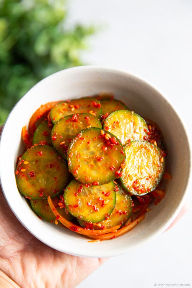 Holding a small bowl of oi muchim in one hand.