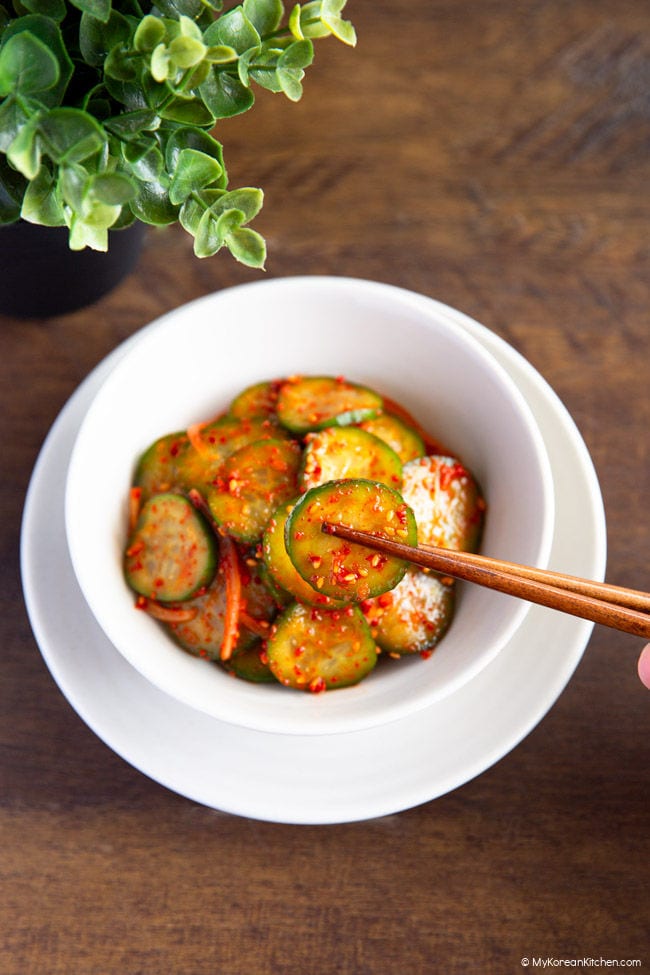 Holding a slice of oi muchim with chopsticks.