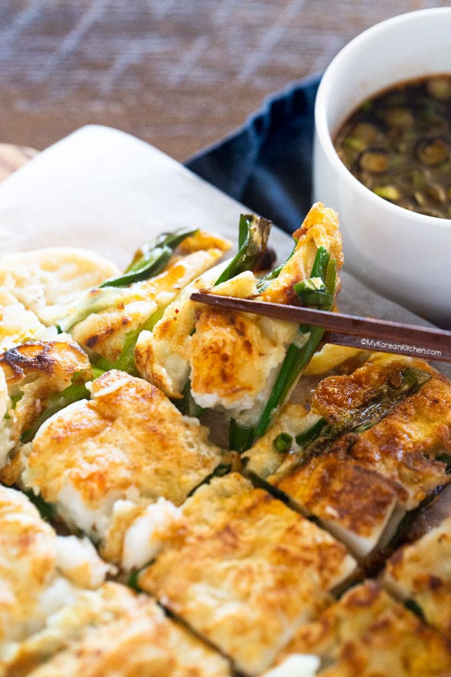 holding a pajeon piece with a pair of chopsticks