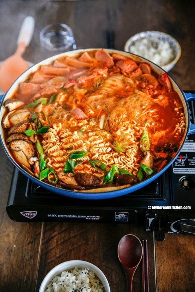 Korean army stew (Budae Jjigae) is a Korean fusion hot pot dish loaded with Kimchi, spam, sausages, mushrooms, instant ramen noodles and cheese. The soup is so comforting and addictive! | MyKoreanKitchen.com