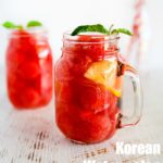 Two glass jugs of Korean watermelon punch, filled with watermelon and ice.