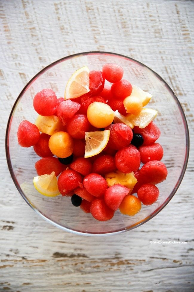 A glass bowl of mixed fruit pieces