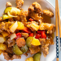 Tangsuyuk served on a white plate with a pair of chopsticks on the side.