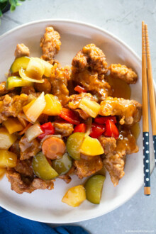 Tangsuyuk served on a white plate with a pair of chopsticks on the side.