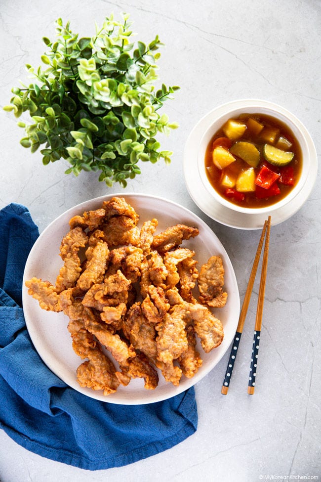 Tangsuyuk served on a white plate with the sweet and sour sauce on the side.