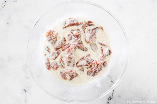 Soaking marinated pork in a bowl of starch water.