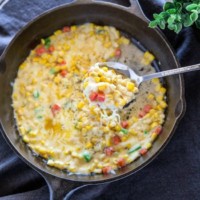 Korean corn cheese is served in a skillet and is scooped with a spoon.