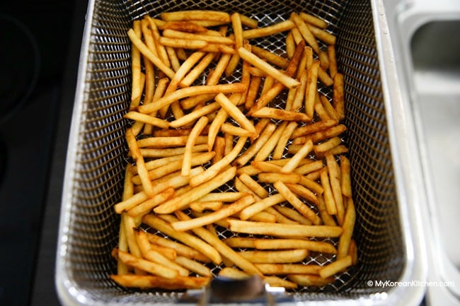Deep fried french fries in a frying basket