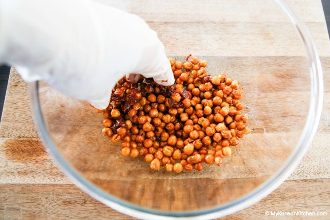 Seasoning roasted chickpeas in a mixing bowl