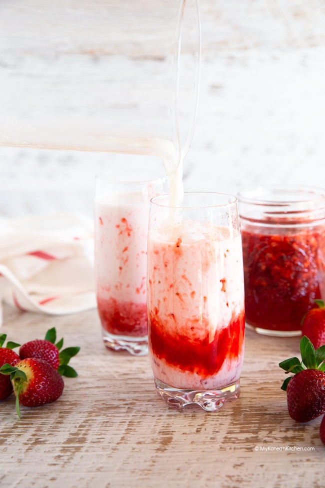 Pouring milk in to a cup with strawberry syrup