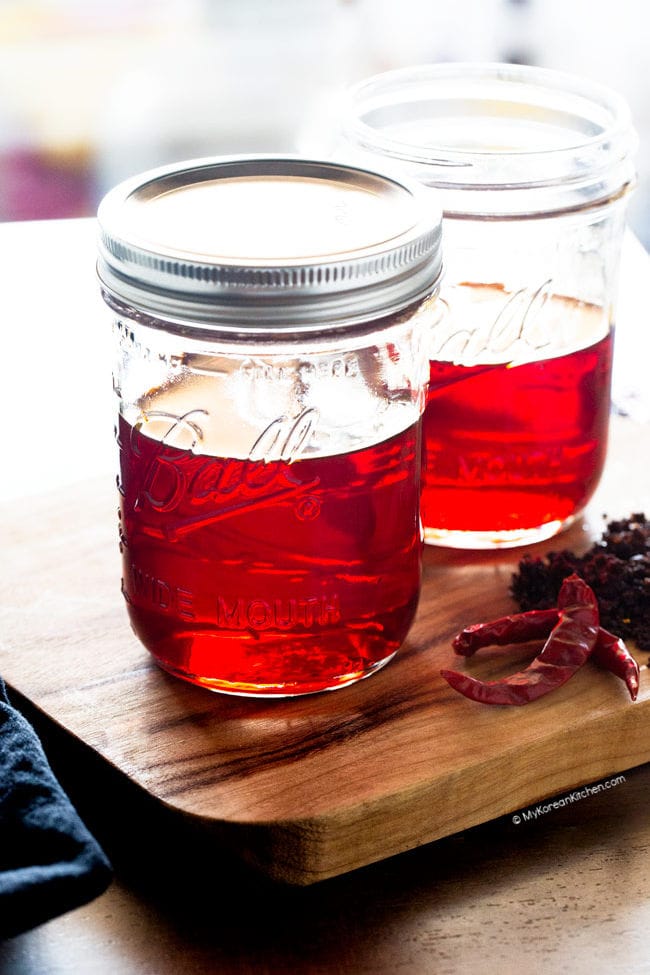 Two jars of Korean chili oil displayed on wooden board