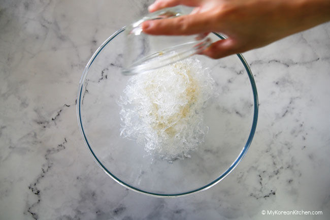 Marinating kelp noodles in a clear mixing bowl