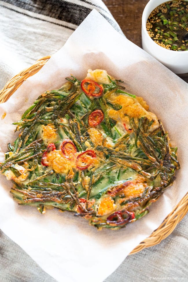 Chive pancake served on wooden plate with dipping sauce