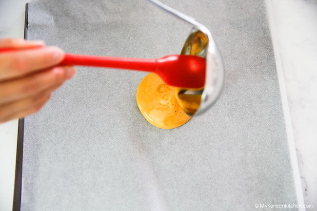 pouring out dalgona mixture using red silicone scraper