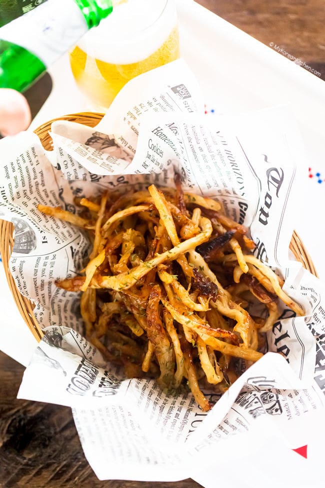 honey butter dried squid served on parchment paper. pouring beer in the background.