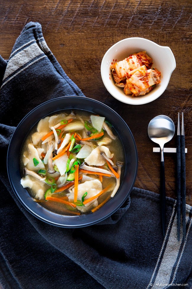 Sujebi served in a black bowl with kimchi.