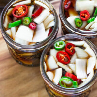 Three open jars filled with chopped onions, sliced chili peppers, and brine.
