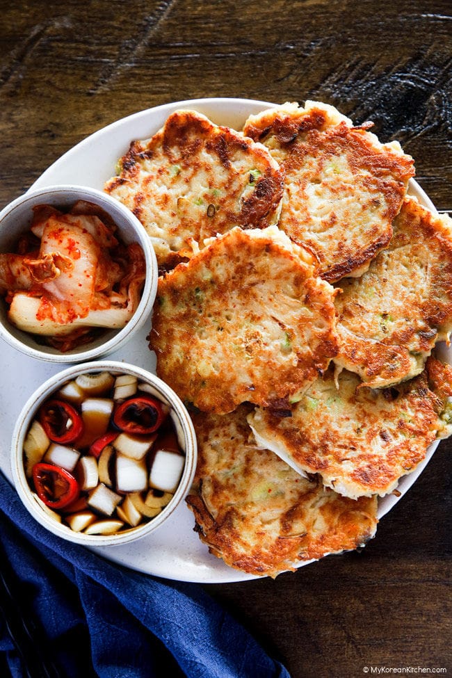 Korean mung bean pancakes served on a white plate with pickled onion and kimchi.