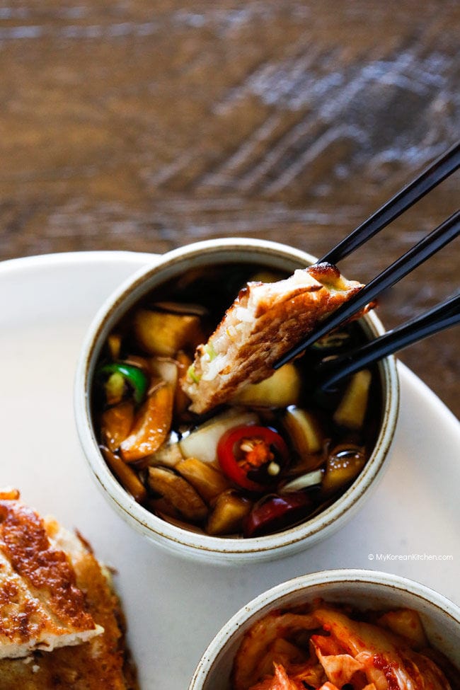 Holding a piece of bindaetteok with chopsticks.
