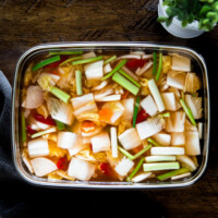 A vertical photo of nabak kimchi in a stainless steel container.