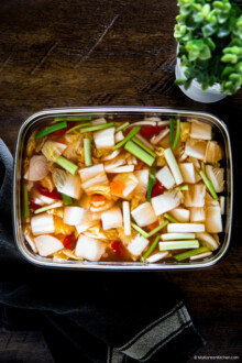 A vertical photo of nabak kimchi in a stainless steel container.