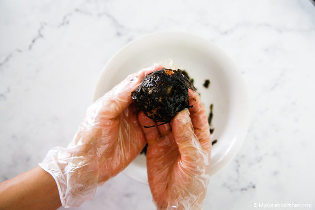 Holding rice balls coated with dried seaweed flakes.