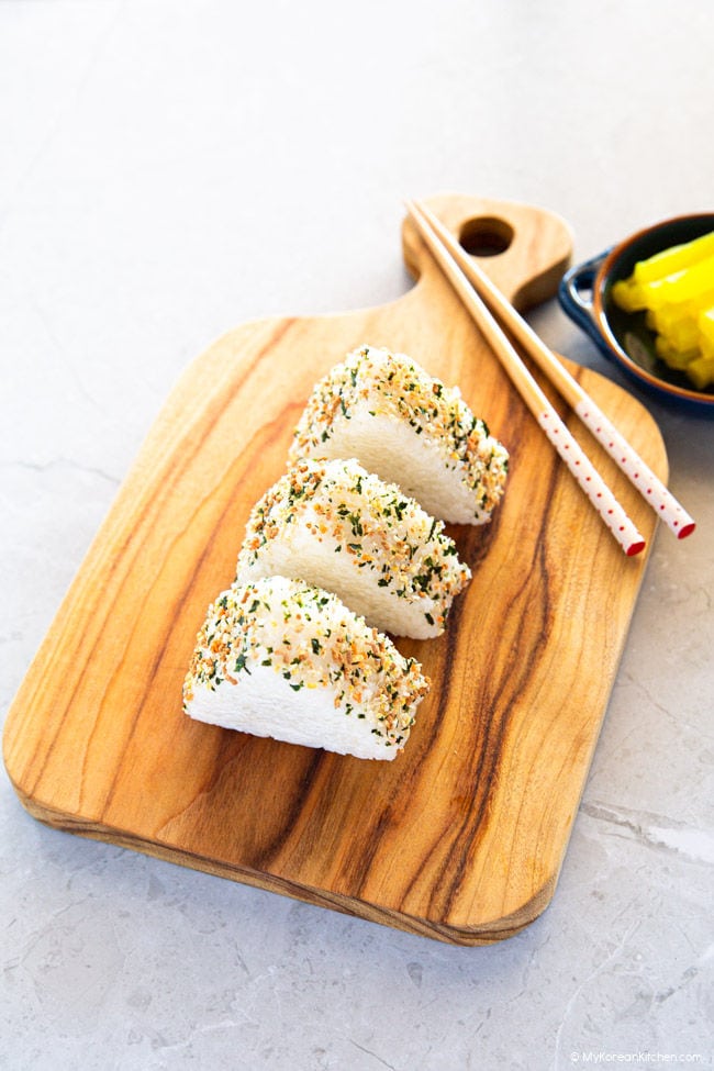 Triangle rice balls served on a wooden board.