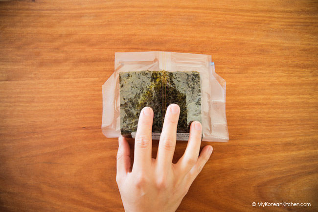 Holding down the dried seaweed with one hand,