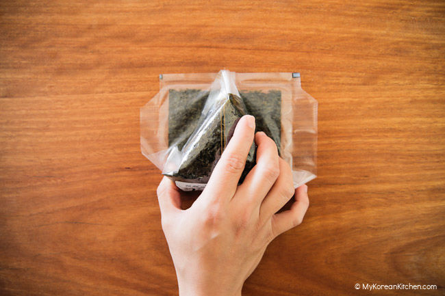Holding down the triangle rice wrapped in dried seaweed.