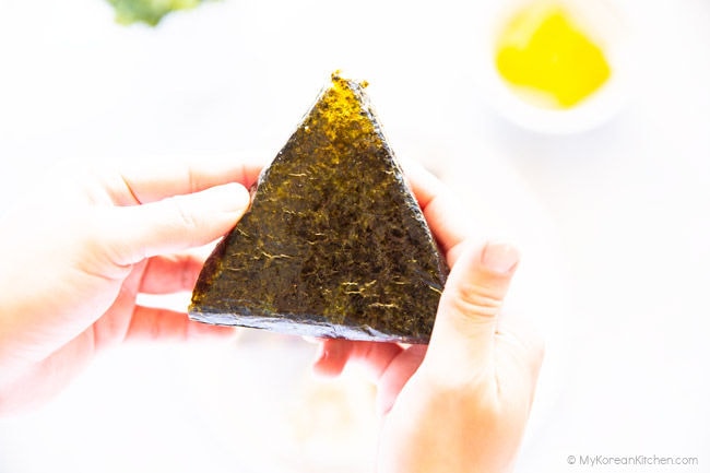 Holding the plastic wrap peeled triangular kimbap with both hands