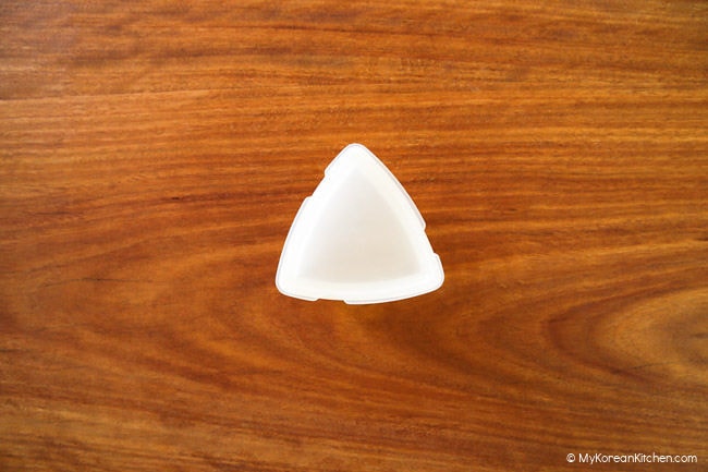 Triangle kimbap mold on a wooden board.