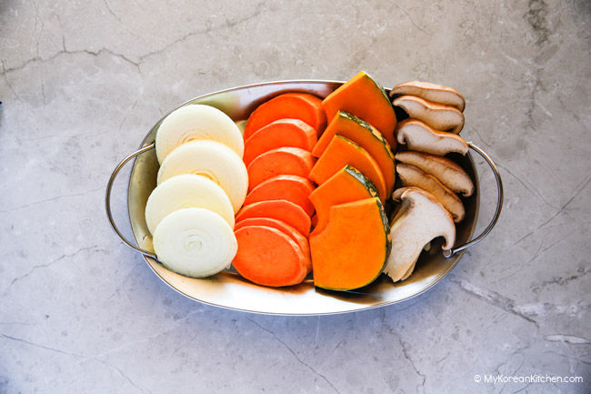 Thinly sliced onion rings, sweet potatoes, pumpkin, mushrooms on a silver tray.